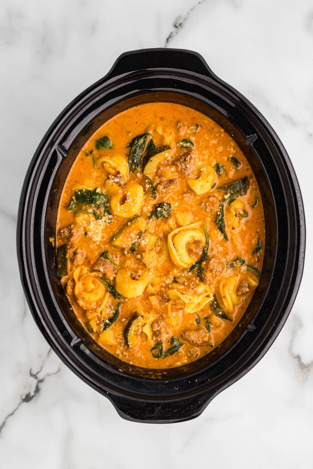 overhead view of black slow cooker with finished tortellini soup