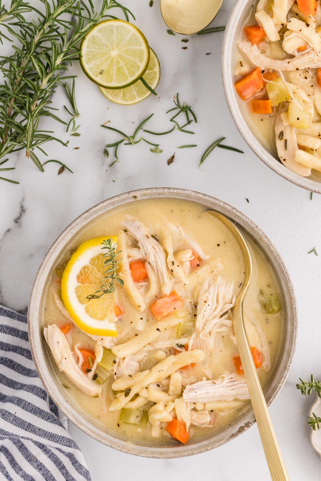 overhead view of two bowls of soup, one with spoon surrounded by sliced limes