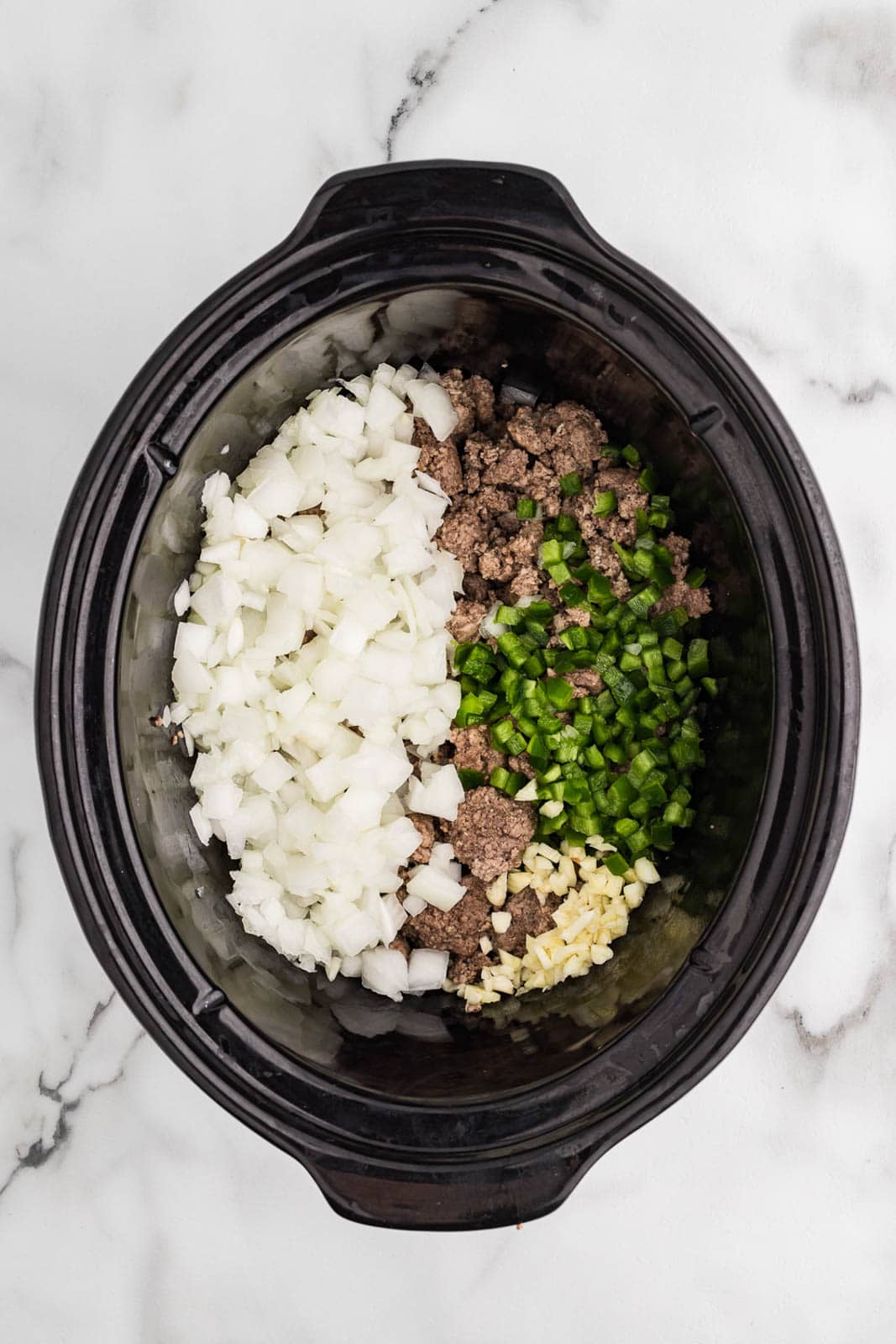 overhead view of black slow cooker with ground beef and turkey, onion, garlic, and jalapeno
