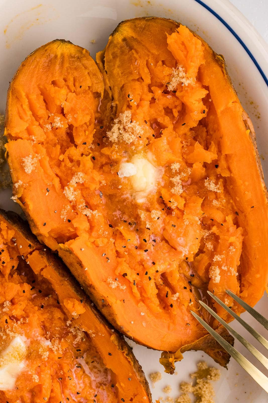 closeup view of slow cooked sweet potato that has been sliced opened with melting butter on top
