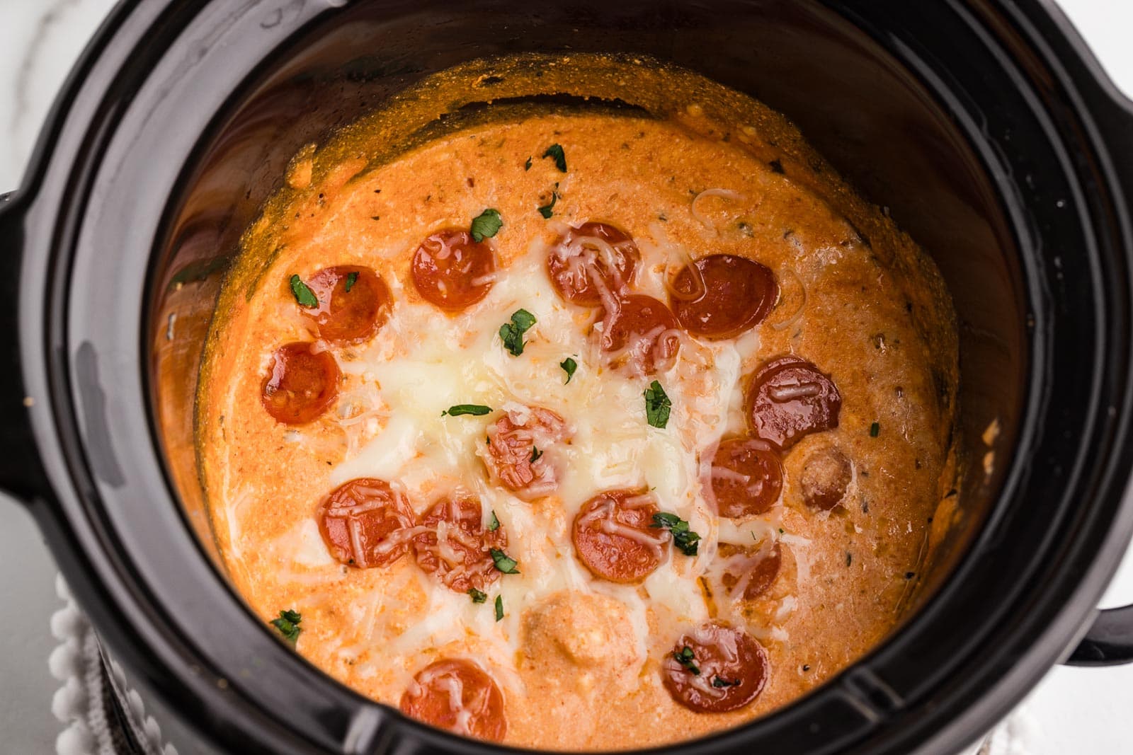 closeup of black slow cooker containing slow cooked pizza dip