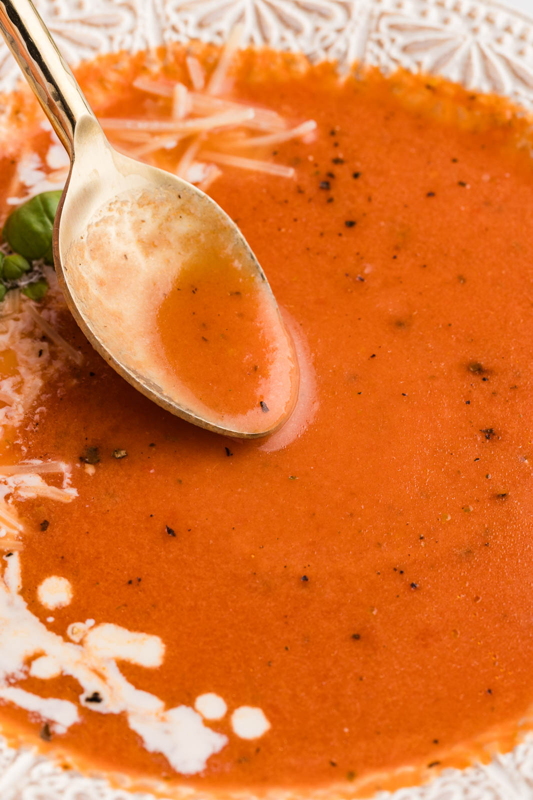 white bowl of tomato soup with spoon inserted