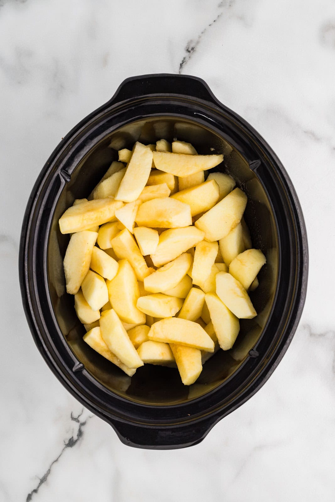 overhead view of black slow Cooker with sliced apples