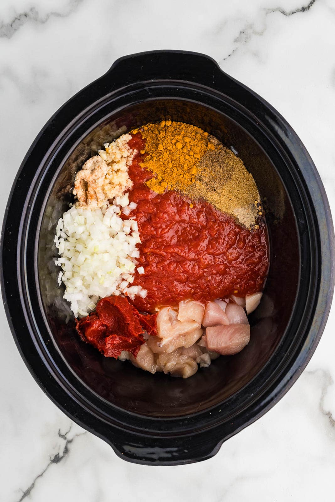 overhead view of black slow cooker with all ingredients except for cream