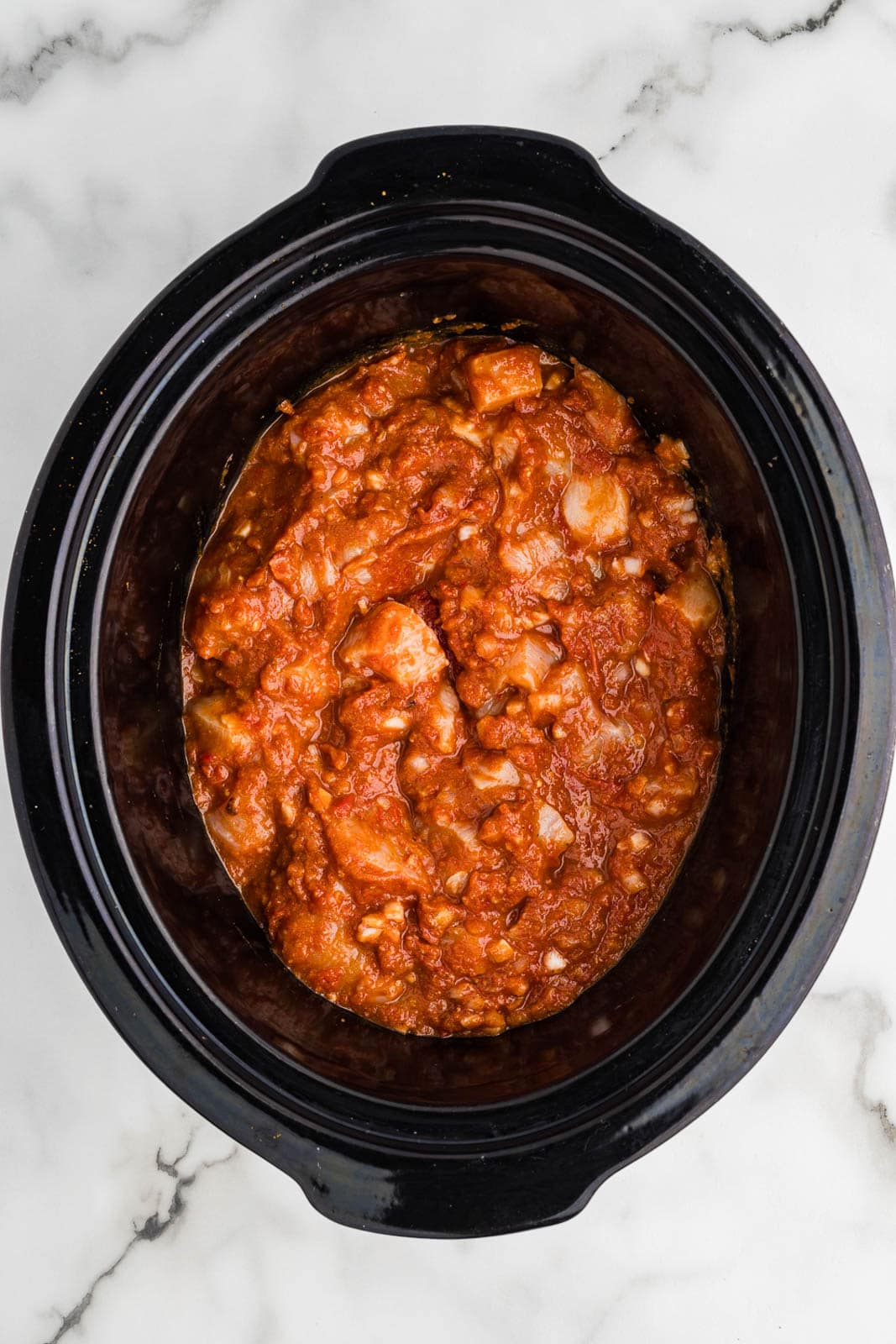 overhead view of black slow cooker with slow cooked chicken mixture