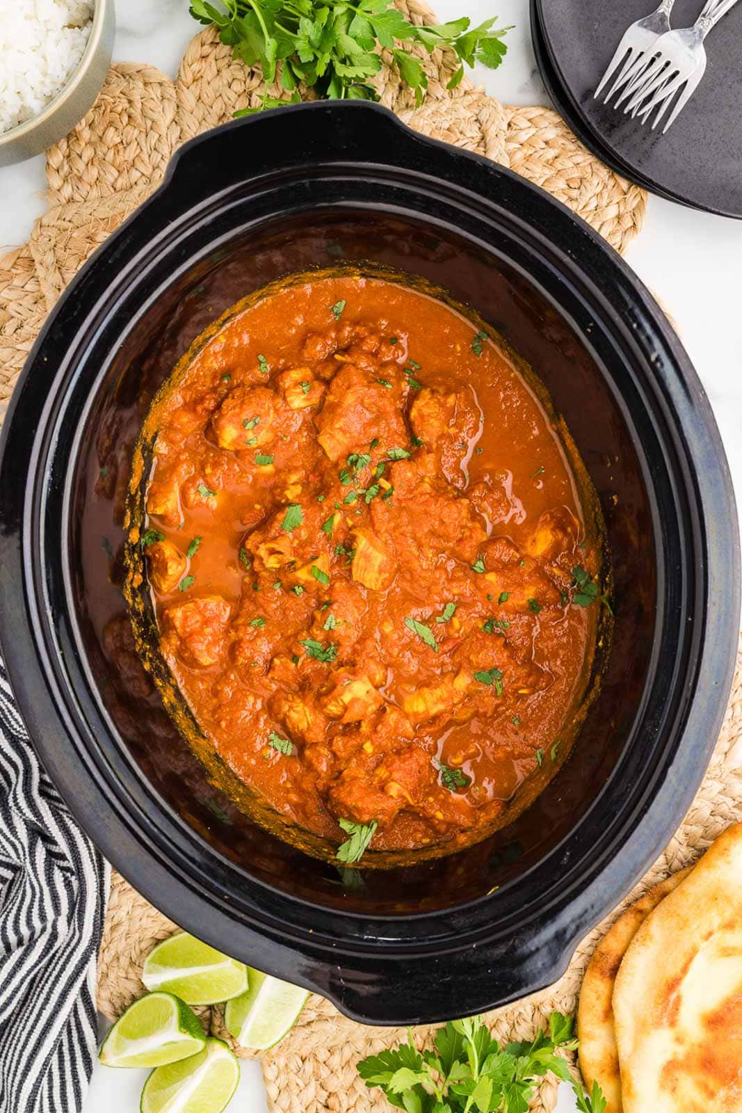 overhead view of black slow cooker with slow cooked chicken mixture with parsley on top