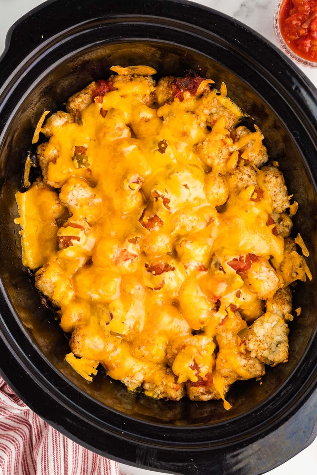 black slow cooker with slow cooked tater tots casserole