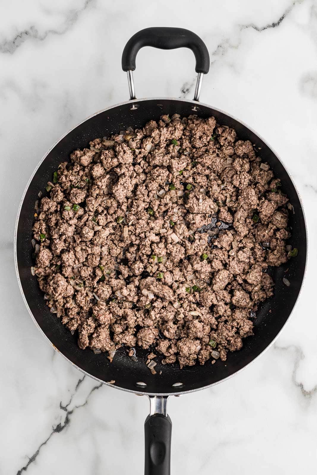 black skillet with cooked ground beef, onion, garlic and jalapeno