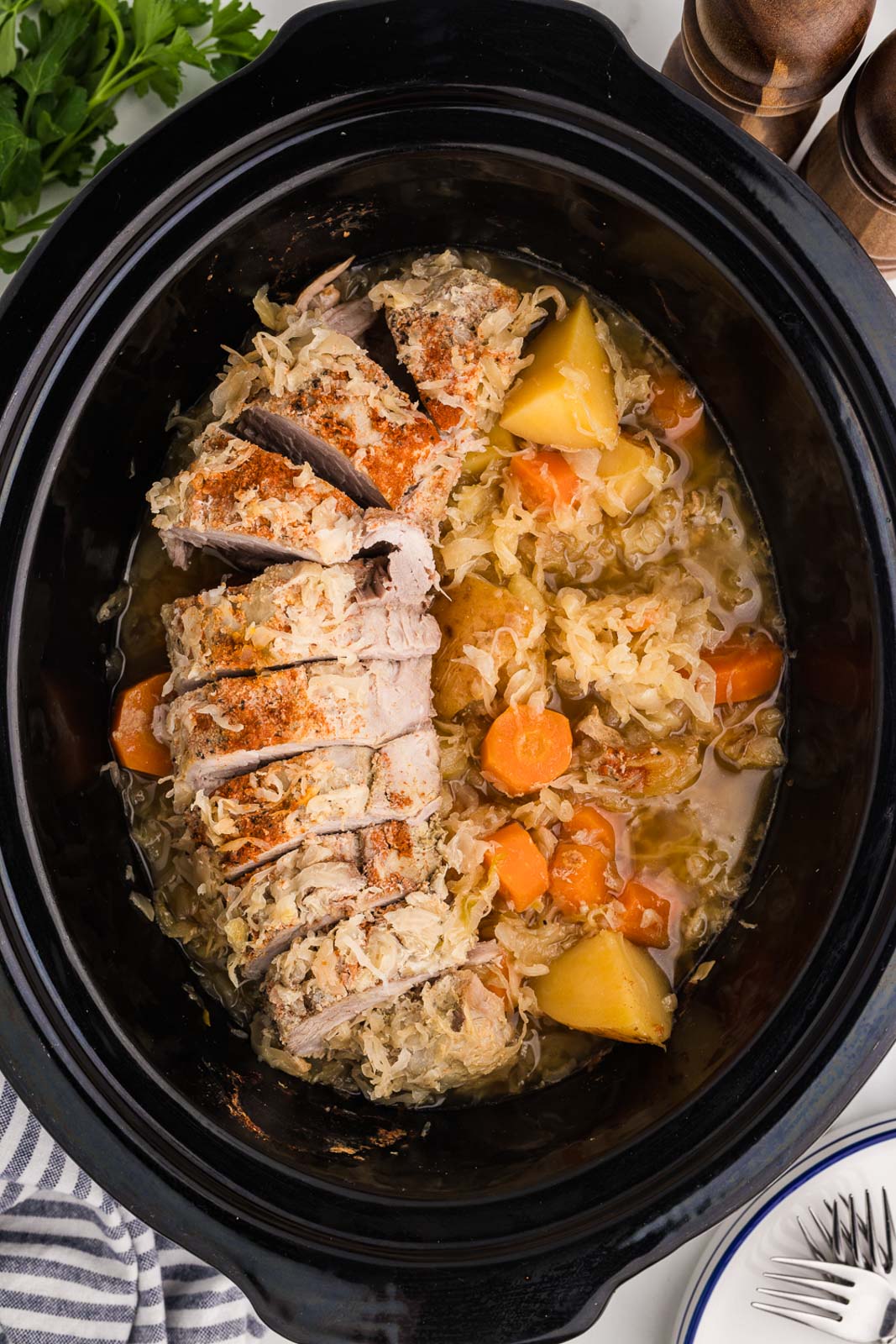 overhead view of slow cooked pork and sauerkraut in black slow cooker