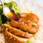 closeup of cooked marinated chicken on a bed of rice with broccoli on side with spoon holding marinade