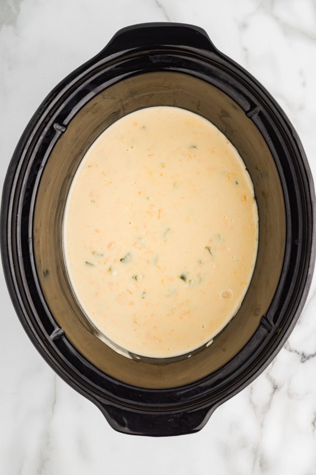 overhead view of black slow cooker with slow cooked jalapeno dip