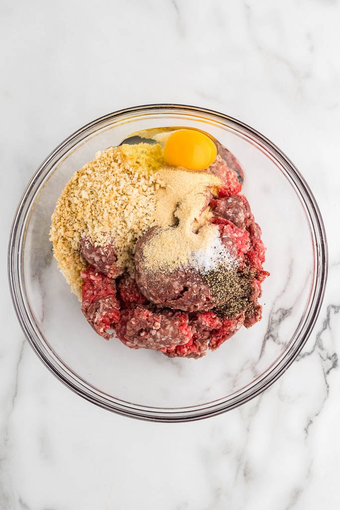 glass bowl with ground beef with egg, breadcrumbs, milk and seasonings
